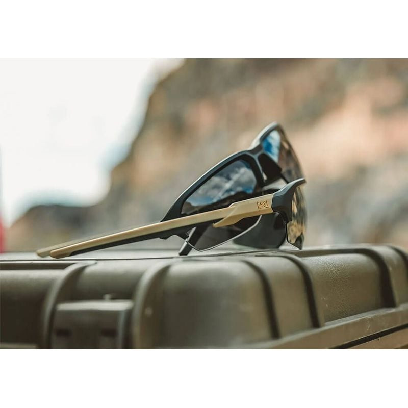 Paire de lunettes Wiley X WX JAKL Tan reposant sur étui militaire en cadre rocheux extérieur ambiant