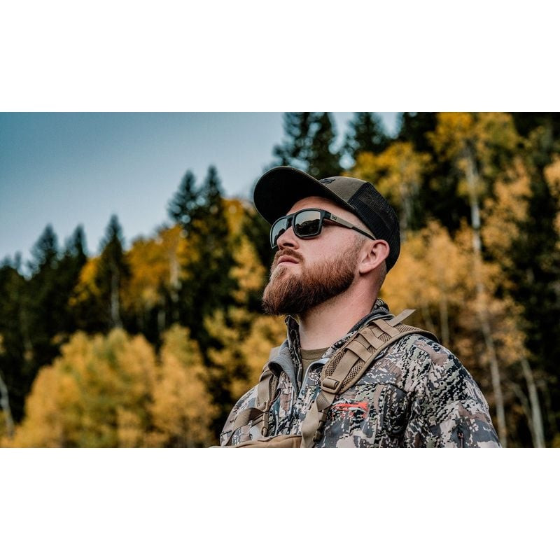 Chasseur barbu avec lunettes Wiley X WX Founder AC6FND04 regardant vers le haut en forêt automnale, 