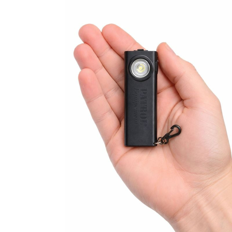 Gros plan de la lampe LED mini Patrol 1047974 tenue en main, montrant sa taille compacte, lentille é