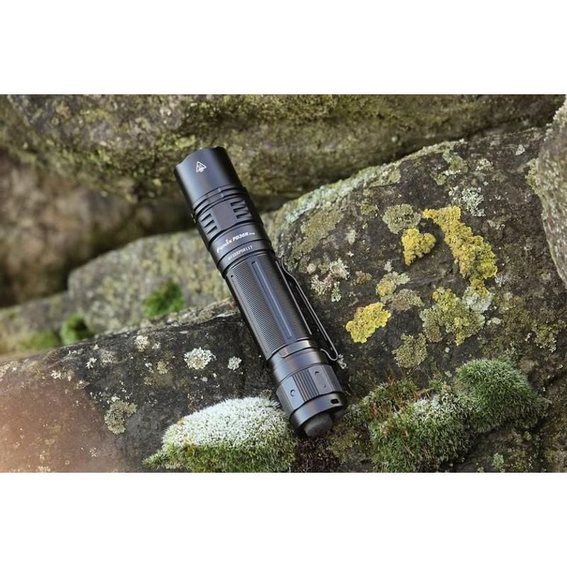 Lampe de poche Fenix PD36R PRO projetant un faisceau lumineux de 2800 lumens dans une forêt sombre l