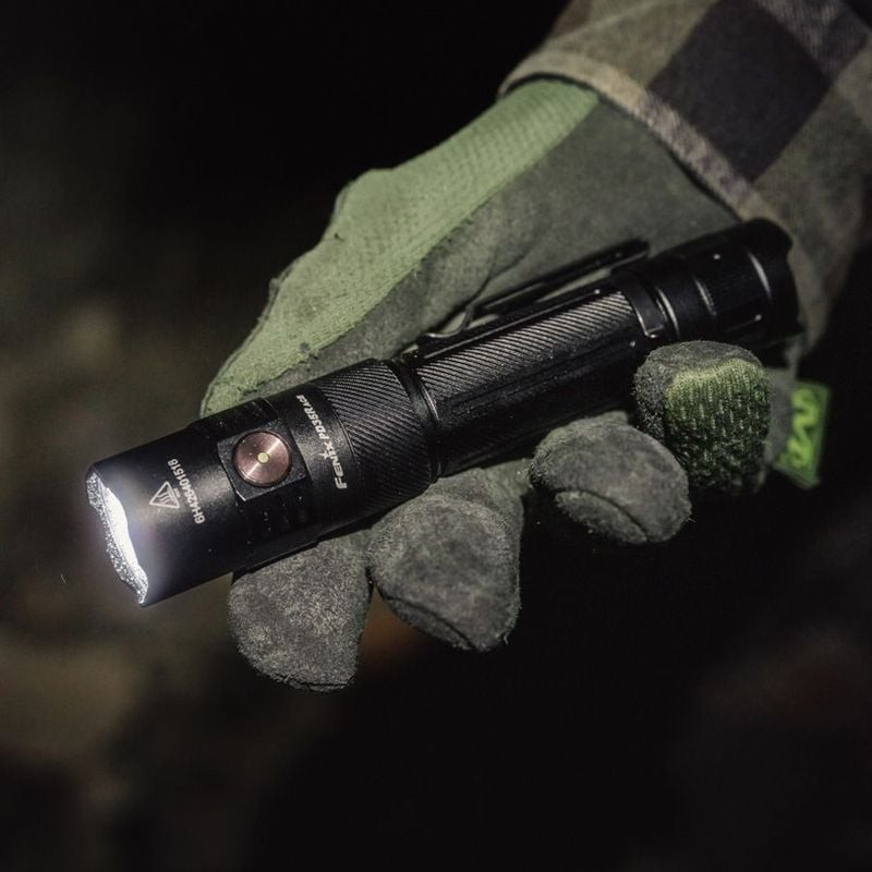 Personne avec lampe de poche Fenix PD35R ACE en extérieur la nuit, démontrant son faisceau puissant 