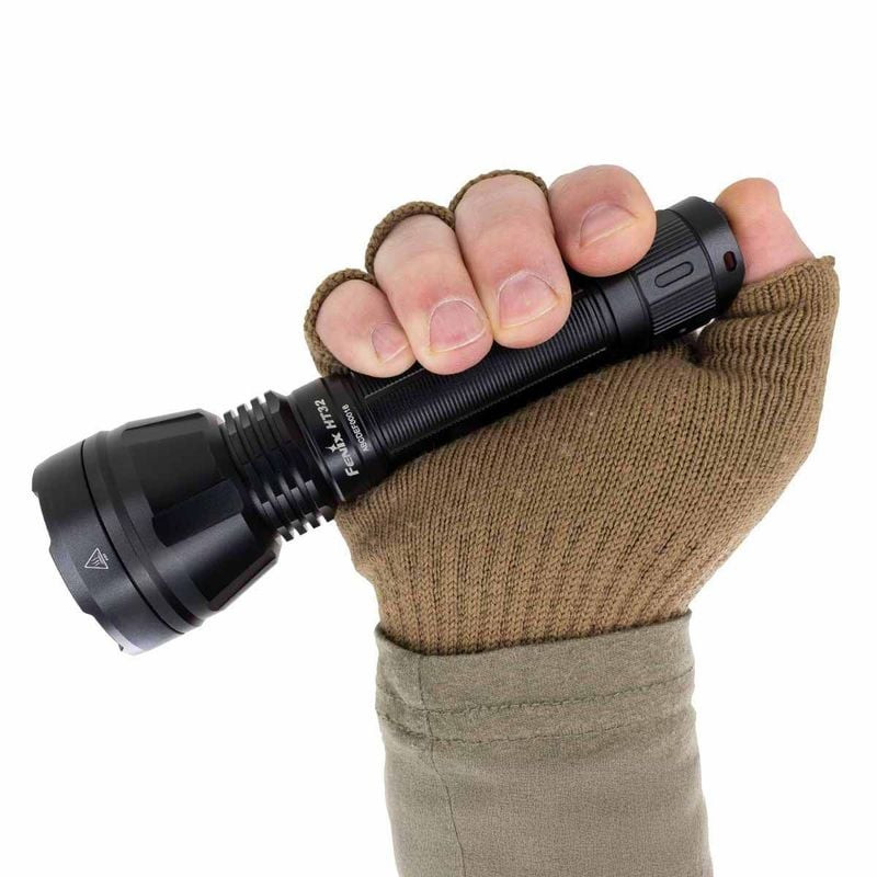 Lampe torche Fenix HT32 en scène de chasse en extérieur, éclairant un chemin la nuit.