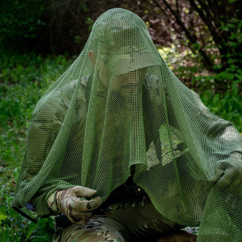 Écharpe filet Vert OD portée lors d'une session airsoft en forêt, camouflage tactique léger et respi
